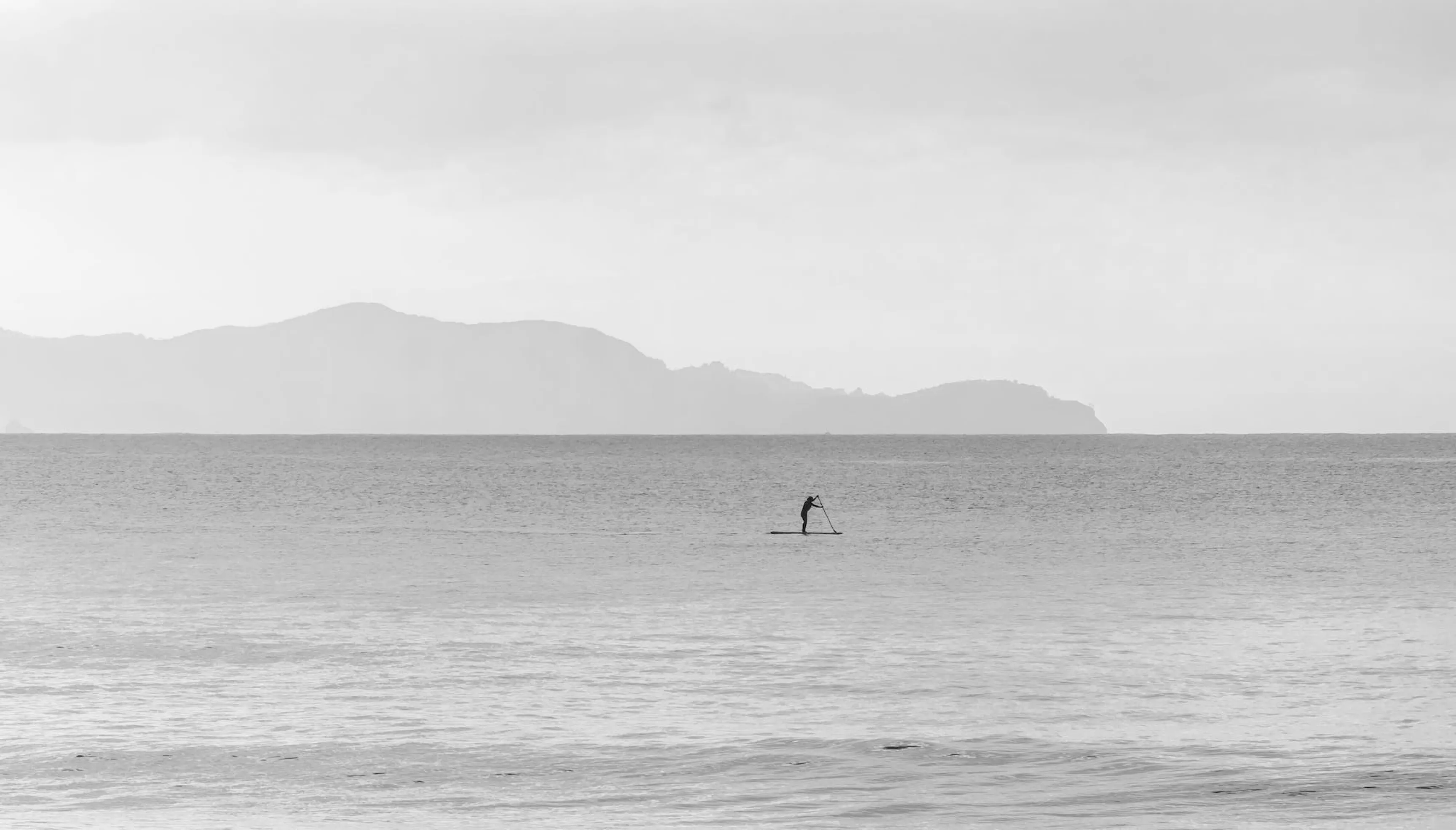 Black and white seascape with a lone man on a sup board